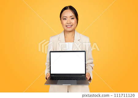 Positive chinese millennial lady in suit, show computer with blank screen, enjoy sale, ad and offer 111711120