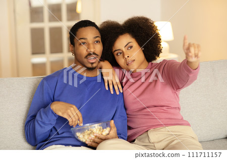 African American spouses watching movies pointing in domestic living room African American spouses watching movies pointing in domestic living room 111711157