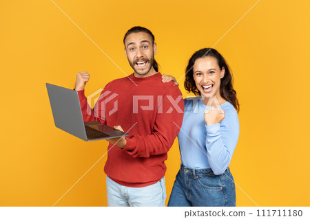 Excited young couple holding and using laptop 111711180