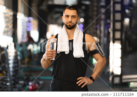 Handsome Young Male Athlete With Water Bottle In Hands Posing At Gym Handsome Young Male Athlete With Water Bottle In Hands Posing At Gym 111711184