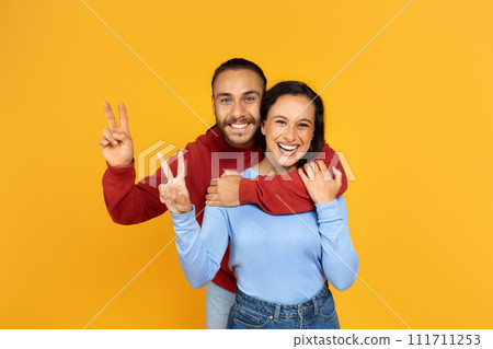 Loving cheerful millennial couple posing on yellow background 111711253