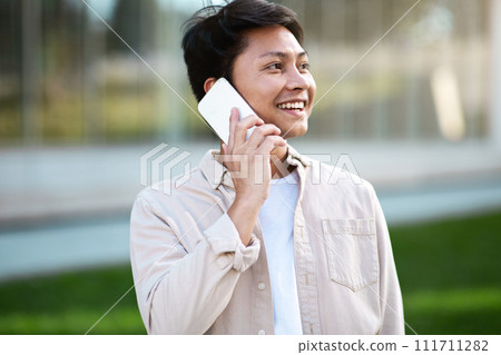 Portrait of cheerful asian guy have phone conversation 111711282