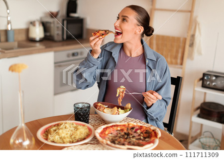 Pregnant woman indulging in pizza and pasta, joyful mealtime 111711309