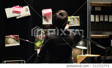 Agent undertaking investigatory services for law enforcement and security, trying to find criminal committing illegal activity. Detective gathering intelligence in incident room. Handheld shot. Agent undertaking investigatory services for law enforcement and security, trying to find criminal committing illegal activity. Detective gathering intelligence in incident room. Handheld shot. 111711773