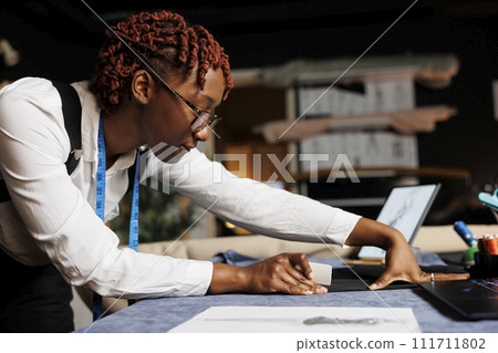 Close up of tailor carefully making sure custom made suit blazer is a perfect fit for comissioning client. Seamstress finishing bespoken sartorial garment for customer in atelier shop workspace Close up of tailor carefully making sure custom made suit blazer is a perfect fit for comissioning client. Seamstress finishing bespoken sartorial garment for customer in atelier shop workspace 111711802