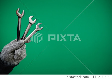 Man's hand holds a spanners isolated. Close up. High resolution product. High quality advertising Green background chromakey free space Man's hand holds a spanners isolated. Close up. High resolution product. High quality advertising Green background chromakey free space 111711998