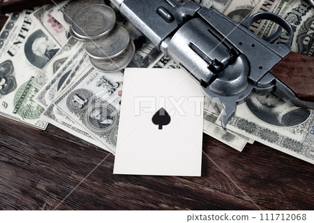 Ace of spades playing card and revolver gun on paper and silver dollars heap. 111712068
