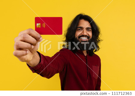 Cheerful young indian guy showing bank card 111712363