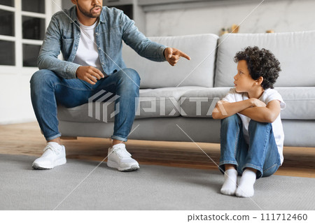 Young black father scolding his preteen son at home, pointing finger 111712460