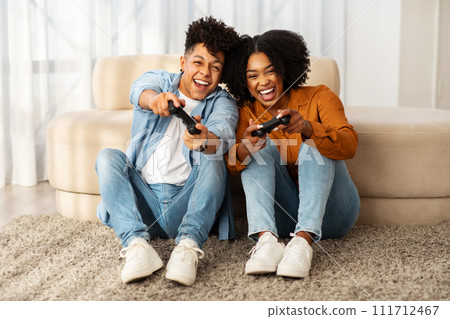 A happy couple sitting on the floor with gaming controllers in hand 111712467