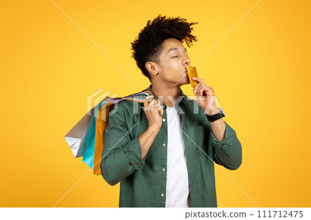 Happy young man going shopping, holding bags and bank card 111712475