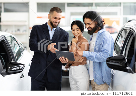 Indian couple checking papers or car specification on digital tablet Indian couple checking papers or car specification on digital tablet 111712601