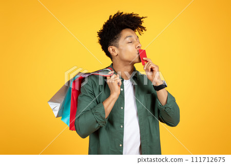 African american guy enjoying sale season, kissing his credit card 111712675