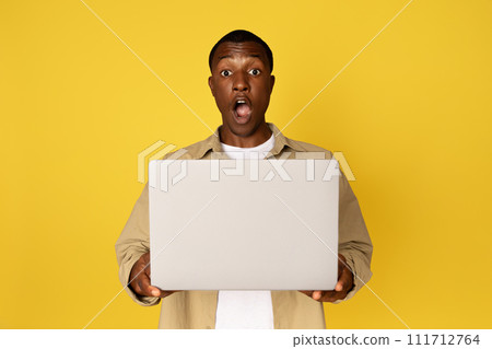 Happy excited millennial black guy in casual with laptop and open mouth, rejoices success Happy excited millennial black guy in casual with laptop and open mouth, rejoices success 111712764