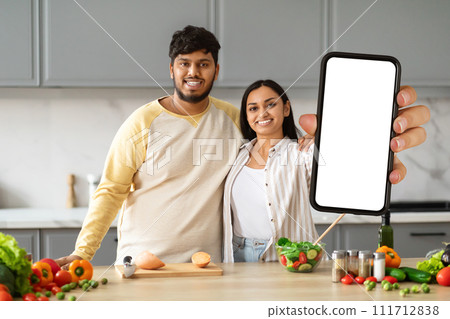 Beautiful loving spouses making food, watching video content on phone Beautiful loving spouses making food, watching video content on phone 111712838