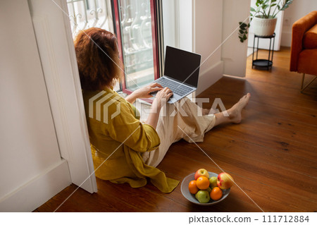 Focused senior woman using laptop with blank screen at home 111712884