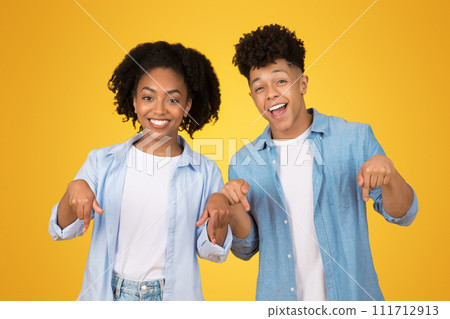 Happy African American young woman and man pointing directly at the camera with cheerful expressions 111712913