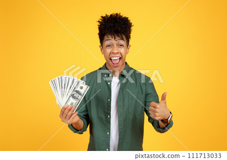 Excited millennial black guy holding money cash in hand 111713033