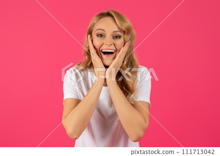 Portrait Of Excited Young Blonde Woman Cupping Face, Pink Background 111713042