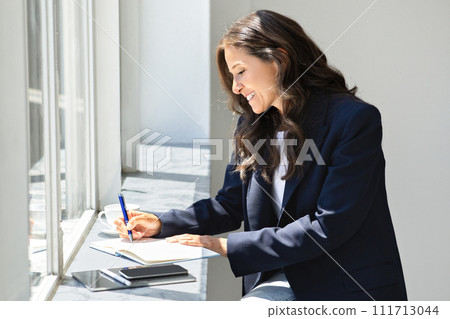 Mature woman real estate agent working while waiting for client 111713044