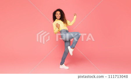 Excited black woman clenching fists, gesturing yes on pink backdrop 111713048