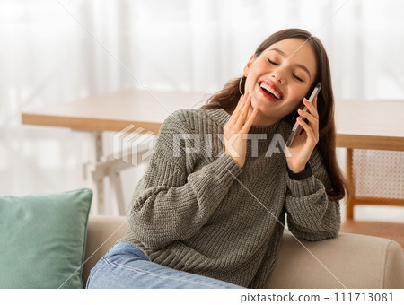 Joyful lady talking on phone and laughing, home interior Joyful lady talking on phone and laughing, home interior 111713081