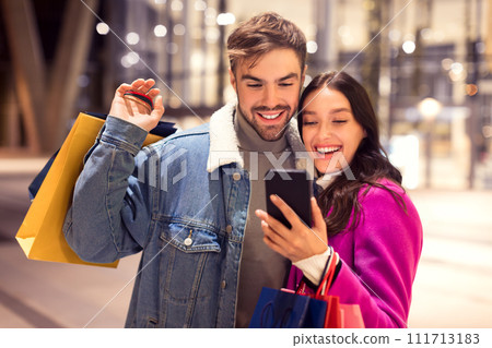 Spouses in winter attire using cellphone application for shopping outdoor Spouses in winter attire using cellphone application for shopping outdoor 111713183