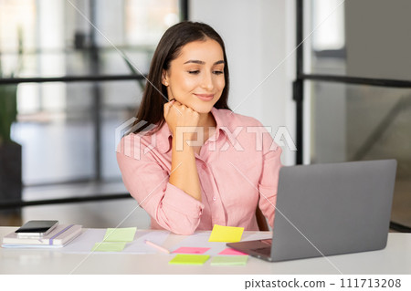 Smiling young arab lady manager with laptop planning day with stickers 111713208