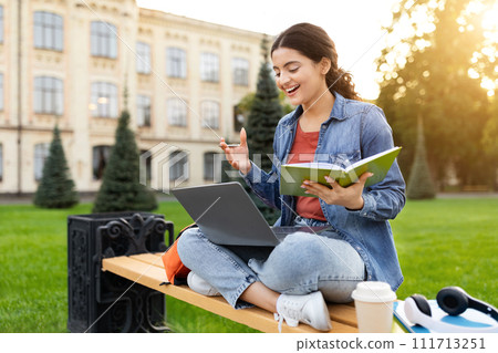 Young indian woman student have online class, sitting on bench Young indian woman student have online class, sitting on bench 111713251