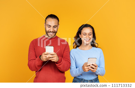 Portrait of cheerful couple holding their smartphones and playing game Portrait of cheerful couple holding their smartphones and playing game 111713332