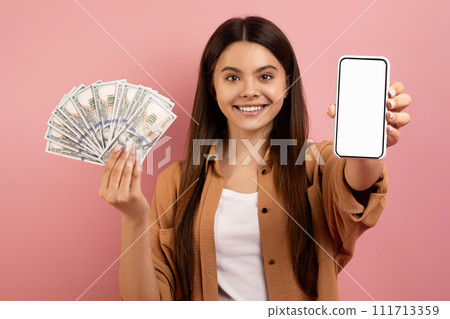 Mobile Banking. Excited Teen Girl Showing Blank Smartphone And Holding Money Cash 111713359