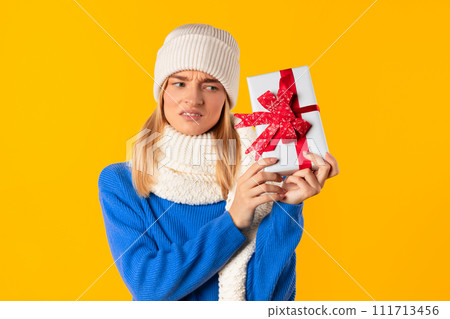 Woman with puzzled expression holding gift 111713456