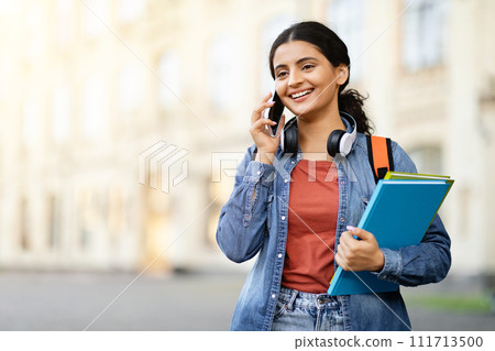 Happy pretty young indian woman student talking on phone outdoor Happy pretty young indian woman student talking on phone outdoor 111713500