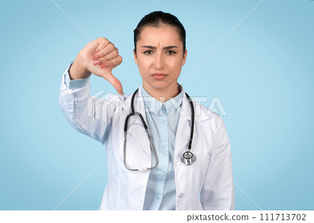 Disapproving female doctor giving thumbs down 111713702