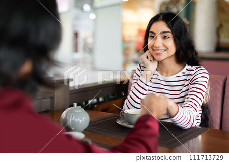 Loving indian couple chatting in coffee shop at lunchtime Loving indian couple chatting in coffee shop at lunchtime 111713729