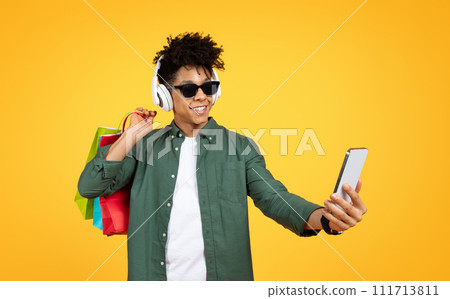 Cool young black guy enjoying shopping, taking selfie on smartphone Cool young black guy enjoying shopping, taking selfie on smartphone 111713811