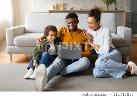 Black family with laptop enjoying time together on floor at home 111713855