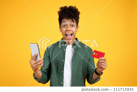Happy black guy with bank card and smartphone on yellow 111713935