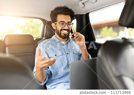 Positive indian businessman working online, going to airport by taxi 111713998