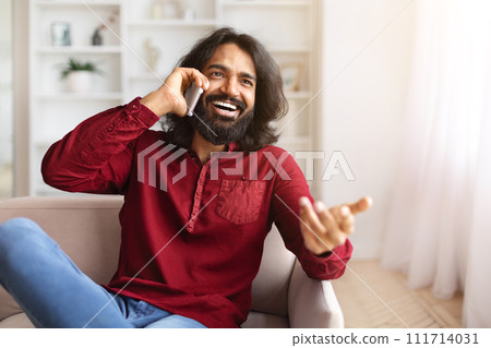 Cheerful indian guy have call on smartphone at home 111714031