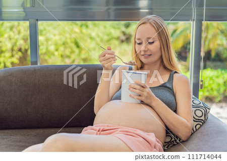 Happy pregnant young woman eating ice cream 111714044