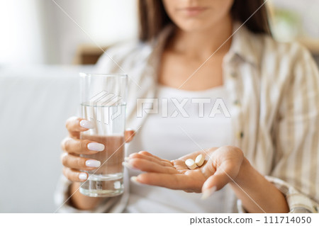 Young Woman Holding Pile Of Pills In Hand And Glass Of Water Young Woman Holding Pile Of Pills In Hand And Glass Of Water 111714050