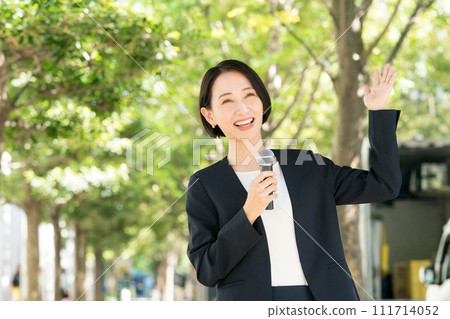 Female announcer with microphone outdoors Female announcer with microphone outdoors 111714052