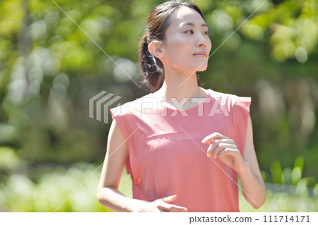 穿著運動服在綠地慢跑的年輕女子 111714171