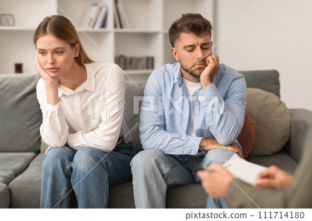 Young married couple sulking sitting on couch at psychotherapist's office 111714180