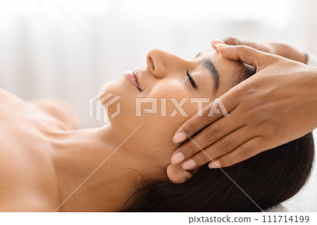 Tranquil beauty with a soothing head rub in a wellness center Tranquil beauty with a soothing head rub in a wellness center 111714199