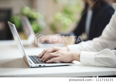 Hands of a businessman operating a computer while having a meeting in the office 111714235
