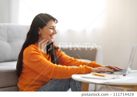 Side view of happy indian lady typing on laptop keyboard Side view of happy indian lady typing on laptop keyboard 111714429