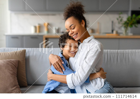 Affectionate mother and son hugging warmly in cozy home setting 111714614