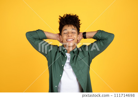 Well-rested young black guy posing with arms behind head 111714698